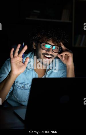 Glücklicher junger indischer Geschäftsmann, der spät in der Nacht Videoanruf hatte. Stockfoto