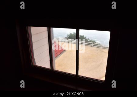 Blick durch das 3-verglaste Glasfenster auf die Dachlinie, den Baum und das Meer Stockfoto