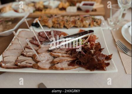 Schneiden verschiedener Fleischsorten. Fleischsnacks auf dem Tisch. Hochzeitsbuffet Stockfoto