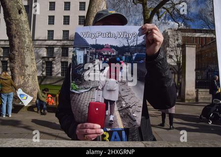 London, Großbritannien. 12. März 2022. Ein Protestler hält ein Plakat mit einem Bild von Flüchtlingen und der Aufschrift „Warum, Putin, Warum?“ Während der Vorführung. Demonstranten versammelten sich vor der Downing Street zur Unterstützung der Ukraine, während Russland seinen Angriff fortsetzt. Kredit: SOPA Images Limited/Alamy Live Nachrichten Stockfoto