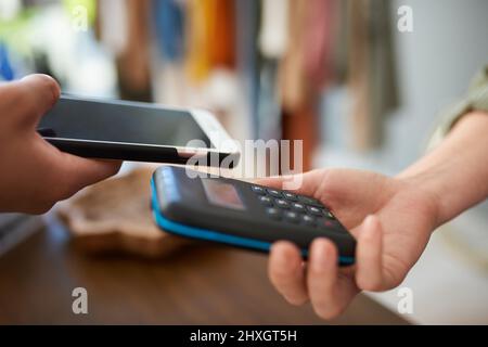 Einfacher. Schneller. Intelligenter. Aufnahme einer Kundin, die ihr Mobiltelefon benutzt, um in einem Geschäft zu bezahlen. Stockfoto