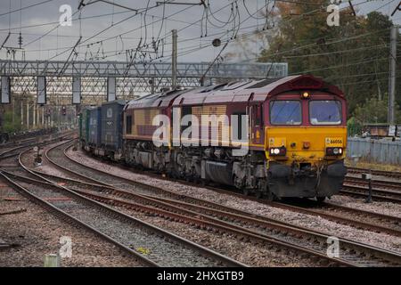 2 DB Cargo Rail UK Baureihe 66 Diesellokomotiven in EWS-Lackierung, die einen Containerzug auf der elektrifizierten Westküsten-Hauptbahnstrecke in Preston schleppen Stockfoto