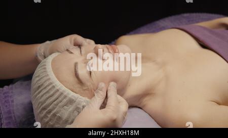 Junge hypnotische Gesichtsfrau erhält Anti-Aging-Gesichtsmassage im Spa-Salon Relax. Wellness Körper Hautpflege Gesicht Schönheitsbehandlung, Verjüngung procedu Stockfoto