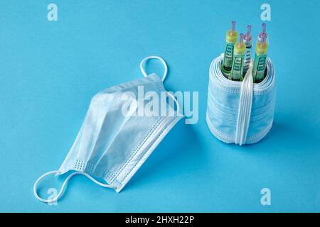 Insulin-Spritzenstifte mit medizinischen Masken auf blauem Hintergrund Stockfoto