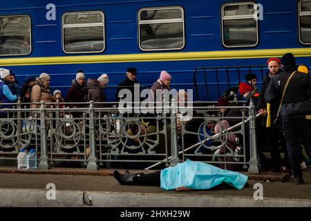 Lviv, Ukraine. 12. März 2022. Ein Blatt bedeckt den Leichnam einer Frau, die im Bahnhof Lwiw-Holovnyi starb. Dies ist zumindest der zweite Tod auf der Station in der letzten Woche. Todesursache, unbekannt. (Bild: © Daniel Carde/ZUMA Press Wire Service) Stockfoto