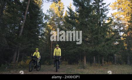 Der Mann und die Frau reisen mit Bikepacking auf gemischtem Terrain. Das Paar fährt mit Fahrradtaschen. Stylisches Bikepacking, Fahrrad, Sportbekleidung Stockfoto