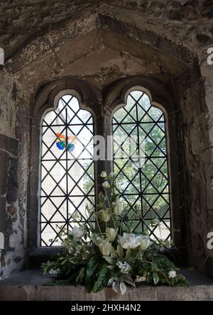 Ein Kirchenfenster und ein Osterblumenarrangement, das für eine Karte geeignet ist Stockfoto