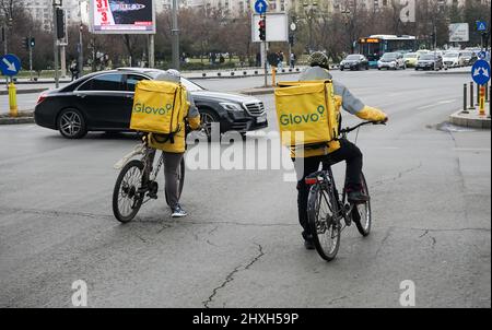 Bukarest, Rumänien - 07. März 2022: Zwei Glovo-Kuriere liefern Lebensmittel in Bukarest, Rumänien. Stockfoto