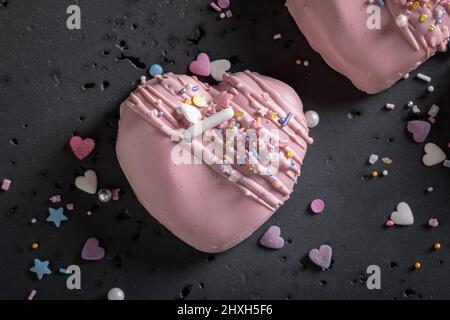 Romantische und leckere Mono-Portion zum valentinstag als besonderen Snack. Rosa Monoportion in Form eines Herzens mit Streuseln. Stockfoto