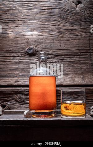 Gereiftem und gutem Cognac im alten Lagerhaus der Destillerie. Whiskey mit Eis in einem Glas im Keller. Stockfoto