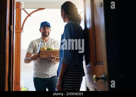 Nun liefern, was Sie brauchen, aus dem Lebensmittelgeschäft. Aufnahme eines Kuriers, der einem Kunden bei sich zu Hause Lebensmittel liefert. Stockfoto