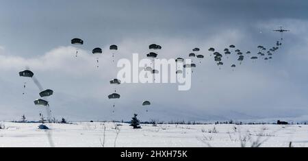 Mitglieder der United States Army Alaska sowie Mitglieder des Bataillons 3., Royal 22e Régiment Canadian Army Fallschirm auf den Boden, nachdem sie aus C-130 und C-17 Flugzeugen über dem Trainingsgebiet von Fort Greenly, Alaska, während der Übung Joint Pacific Multinative Readiness Center 22-02 am 12. März 2022 gesprungen sind. Bildnachweis: Meister Sailor Dan Bard Kanadische Streitkräfte Kampfkamera Stockfoto