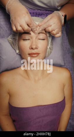 Junge hypnotische Gesichtsfrau erhält Anti-Aging-Gesichtsmassage im Spa-Salon Relax. Wellness Körper Hautpflege Gesicht Schönheitsbehandlung, Verjüngung procedu Stockfoto