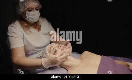 Junge hypnotische Gesichtsfrau erhält Anti-Aging-Gesichtsmassage im Spa-Salon Relax. Wellness Körper Hautpflege Gesicht Schönheitsbehandlung, Verjüngung procedu Stockfoto