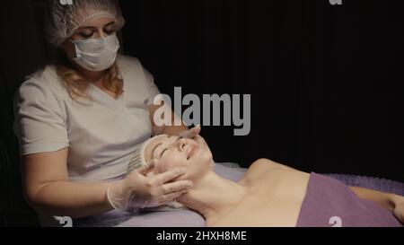 Junge hypnotische Gesichtsfrau erhält Anti-Aging-Gesichtsmassage im Spa-Salon Relax. Wellness Körper Hautpflege Gesicht Schönheitsbehandlung, Verjüngung procedu Stockfoto
