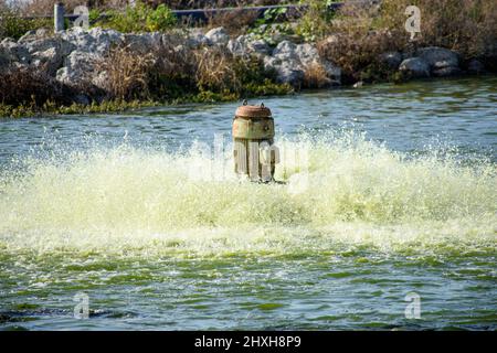 Rostige Pumpe belüftet und filtert kontaminiertes Wasser in der Kläranlage Teich, um Schadstoffe und gelöste Gase zu entfernen. Stockfoto