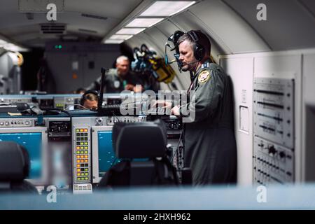 Die Besatzung der NATO Airborne Early Warning and Control Force saß vor Bildschirmen an Bord einer NATO Boeing 707 E-3A AWACS. Diese Flugzeuge patrouillieren den alliierten Luftraum in Osteuropa nach dem russischen Angriff auf die Ukraine. Das Flugzeug des NATO-Airborne Warning & Control System Boeing E-3A verfügt über eine markante Radarkuppel, die auf dem Rumpf montiert ist und es der Besatzung ermöglicht, eine Fläche von mehr als 310.798 Quadratkilometern oder etwa der Größe Polens zu begutachten. (NATO-Foto) Stockfoto