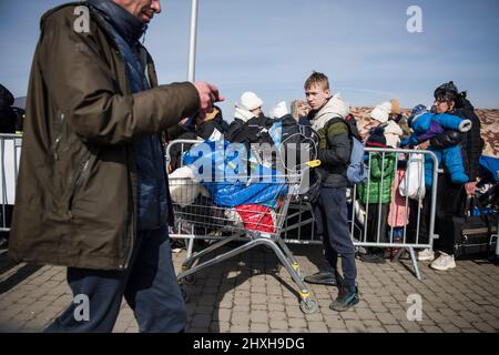 Medyka, Polen. 12. März 2022. Ukrainische Flüchtlinge stehen Schlange, um an Bord eines Reisebusses zu gehen, der Flüchtlinge nach Przemysl bringt. Ukrainische Flüchtlinge am Grenzübergang Medyka am 16.. Tag der russischen Invasion in der Ukraine. Kredit: SOPA Images Limited/Alamy Live Nachrichten Stockfoto