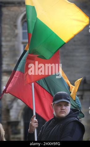 Peterborough, Großbritannien. 12. März 2022. Ein Mitglied der litauischen Gemeinschaft hält seine Nationalflagge. Zu einer Zeit, in der die Ukraine von Wladimir Putins Russland angegriffen wird, feiern die Litauer ihren Unabhängigkeitstag zur Wiederherstellung in der Peterborough-Kathedrale. Sie stehen zur Unterstützung der Ukraine und halten ukrainische Flaggen und Bänder fest. Am 11. 1990. März erlangte Litauen seine Freiheit aus der Sowjetunion zurück. Ein kurzes Gebet und eine Schweigeminute wurden für die gefallenen Verteidiger der Freiheit gehalten. Kredit: SOPA Images Limited/Alamy Live Nachrichten Stockfoto