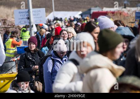 Medyka, Polen. 12. März 2022. Ukrainische Flüchtlinge stehen Schlange, um an Bord eines Reisebusses zu gehen, der Flüchtlinge nach Przemysl bringt. Ukrainische Flüchtlinge am Grenzübergang Medyka am 16.. Tag der russischen Invasion in der Ukraine. Kredit: SOPA Images Limited/Alamy Live Nachrichten Stockfoto