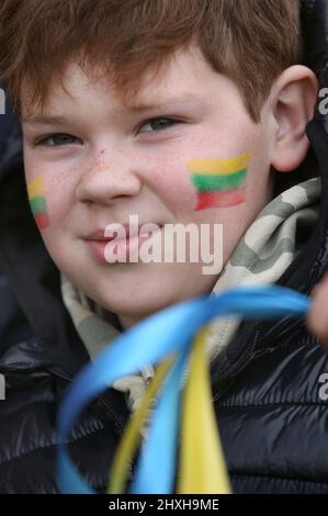 Peterborough, Großbritannien. 12. März 2022. Ein Kind mit einer litauischen Flagge auf seiner Wange winkt ukrainische Farbbänder. Zu einer Zeit, in der die Ukraine von Wladimir Putins Russland angegriffen wird, feiern die Litauer ihren Unabhängigkeitstag zur Wiederherstellung in der Peterborough-Kathedrale. Sie stehen zur Unterstützung der Ukraine und halten ukrainische Flaggen und Bänder fest. Am 11. 1990. März erlangte Litauen seine Freiheit aus der Sowjetunion zurück. Ein kurzes Gebet und eine Schweigeminute wurden für die gefallenen Verteidiger der Freiheit gehalten. (Foto von Martin Pope/SOPA Images/Sipa USA) Quelle: SIPA USA/Alamy Live News Stockfoto