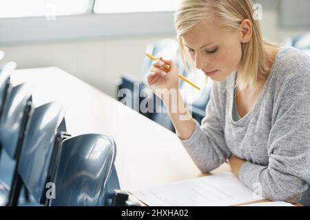 Konzentriert sich auf ihre Studien. Ein schöner Student, der in einem Klassenzimmer studiert. Stockfoto