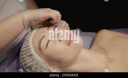 Junge hypnotische Gesichtsfrau erhält Anti-Aging-Gesichtsmassage im Spa-Salon Relax. Wellness Körper Hautpflege Gesicht Schönheitsbehandlung, Verjüngung procedu Stockfoto