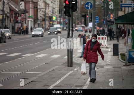 Bild einer weißen Kaukasierin, die in den Straßen von Belgrad, Serbien, läuft, während sie eine schützende Gesichtsmaske trägt, während der 2020 Stockfoto