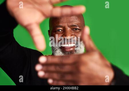 Ihr Lächeln ist das, was jeder sehen möchte. Studioaufnahme eines älteren Mannes, der vor seinem Gesicht einen Fingerrahmen bildet. Stockfoto