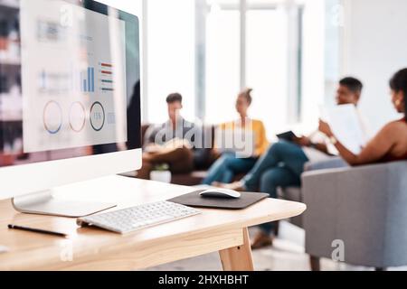 Es ist immer geplant, die Gewinne zu steigern. Aufnahme einer Grafik auf einem Computerbildschirm in einem Büro mit einer Gruppe von Geschäftsleuten im Hintergrund. Stockfoto