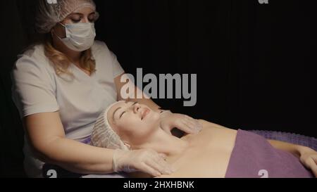 Junge hypnotische Gesichtsfrau erhält Anti-Aging-Gesichtsmassage im Spa-Salon Relax. Wellness Körper Hautpflege Gesicht Schönheitsbehandlung, Verjüngung procedu Stockfoto