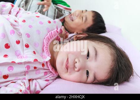 Nahaufnahme asiatische Geschwister glücklich im Bett vor dem Schlafen. Konzeptuelles Bild über Liebe und Bindung von Geschwisterchen. Glückliche Familie, die Zeit zusammen verbringt. Stockfoto