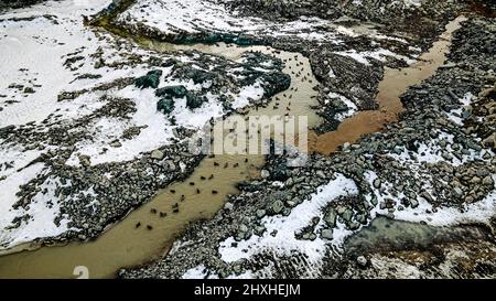 Schnee schmilzt im Steinbruch, als sich der Frühling nähert und Enten im Wasser sitzen Stockfoto