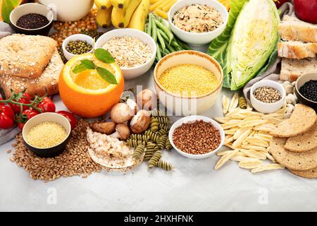 Auswahl an guten Kohlenhydrat-Quellen - Gemüse, Obst, Getreide, Hülsenfrüchte, Nüsse und Samen auf weißem Hintergrund, Draufsicht. Stockfoto