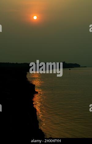 Es ist die Zeit des Sommeruntergangs. Es ist eine malerische Landschaft des Sonnenuntergangs an einem Flussufer. Viele Touristen kommen hierher, um die Landschaft zu sehen. Stockfoto