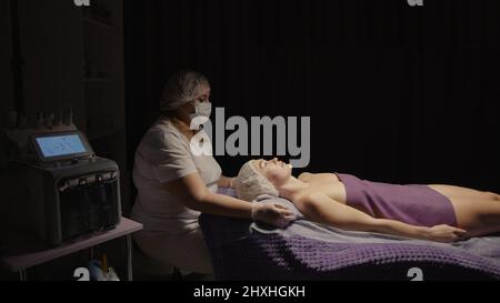 Junge hypnotische Gesichtsfrau erhält Anti-Aging-Gesichtsmassage im Spa-Salon Relax. Wellness Körper Hautpflege Gesicht Schönheitsbehandlung, Verjüngung procedu Stockfoto