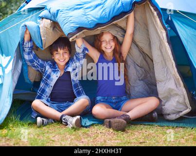 Camping und viel Spaß. Porträt eines jungen Bruders und einer Schwester, die in ihrem Zelt sitzen. Stockfoto