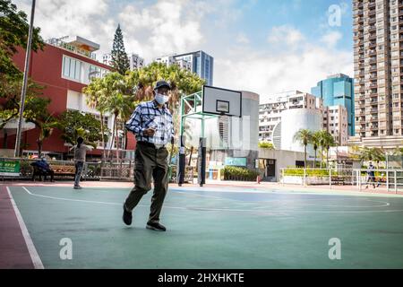 Hongkong. 01. März 2022. Ein älterer Hongkonger dreht um einen leeren Basketballplatz in North Point. Angesichts der zunehmenden Fälle in Hongkong hat die Abteilung für Freizeit- und Kulturdienste alle Spielplätze, Freizeiteinrichtungen, Grillplätze, Campingplätze geschlossen und sie haben begrenzte Sitzplätze an allen öffentlichen Plätzen, um Versammlungen zu reduzieren. (Foto von Ben Marans/SOPA Images/Sipa USA) Quelle: SIPA USA/Alamy Live News Stockfoto