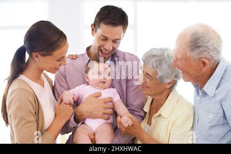 Wir lieben die neueste Ergänzung unserer Familie. Aufnahme einer Familie aus drei Generationen, die ein Baby anbetend. Stockfoto