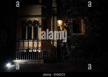 Jim, ein Feuerzeugingenieur für Gaslampen von British Gas, dreht die mechanische Uhr der ältesten Gaslampe in England, in Dean's Yard, Westminster Abbey, London, Die seit über 200 Jahren im Einsatz ist und früher eine Öllampe war. In Westminster sind noch immer über 300 Gaslampen vorhanden, und rund 1.500 Gaslampen, die 200 Jahre alt sind, leuchten weiterhin die Hauptstadt. Bilddatum: Dienstag, 8. März 2022. Stockfoto