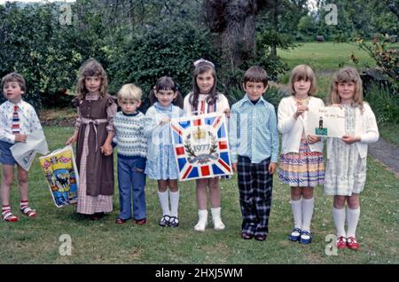 Eine Gruppe britischer Kinder, die am 7. Juni 1977 zusammenkommen, um das Silberjubiläum von Königin Elizabeth II. Zu feiern Hier halten die Kinder Plastikträger mit Jubilee-Bildern auf sich. Seltsamerweise halten zwei Kinder eine Zeichnung der TV-Comedy-Figur Mr Bean (die Worte lauten ‘This is ‘Mr Bene’). Dieses Bild stammt von einem alten Kodak-Amateurfotograf mit Farbtransparenz – einem Vintage-Foto aus dem Jahr 1970s. Stockfoto