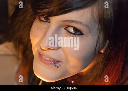 Junge Punk-Emo Girl mit Piercing, mit roten und schwarzen Haaren, lächelnd auf die Kamera, Blick aus dem hohen Winkel, Nahaufnahme Stockfoto