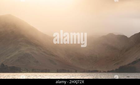 Atemberaubendes Landschaftsbild von Buttermere im Lake District bei Sonnenaufgang im Herbst mit dramatischem stürmischen Himmel Stockfoto