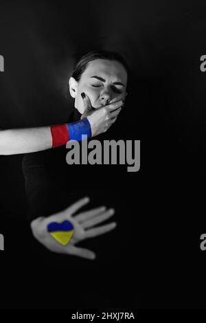Russland begann den Krieg in der Ukraine am 24.02.2022. Schwarz-weißes Foto einer ukrainischen Frau, die von der Russischen Föderation mit ihrem Mund bedeckt ist. Stockfoto