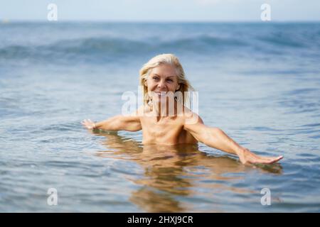 Elderige Frau in gutem Zustand, die im Meer baden. Stockfoto