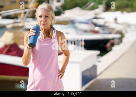 Ältere Sportlerin, die während des Trainings Wasser trinkt Stockfoto