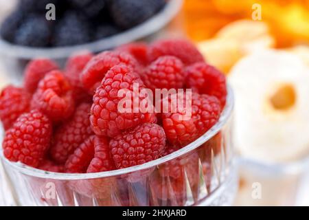 Glas mit frischen roten Himbeeren in der Nähe auf dem Tisch Stockfoto