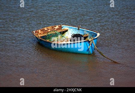 Ein kleines Boot mit Angelausrüstung vor Anker in Overy Creek an der North Norfolk Küste in Burnham Overy Staitthe, Norfolk, England, Vereinigtes Königreich. Stockfoto