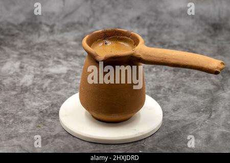 Türkischer Kaffee in einer irdenen Kanne auf dunklem Hintergrund. Geschmack der traditionellen türkischen Küche. Nahaufnahme Stockfoto