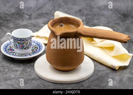 Türkischer Kaffee in einer irdenen Kanne auf dunklem Hintergrund. Geschmack der traditionellen türkischen Küche. Nahaufnahme Stockfoto